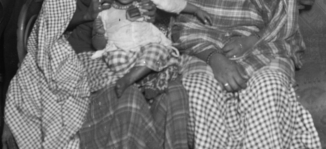 Photo of two women seated, one holding a baby