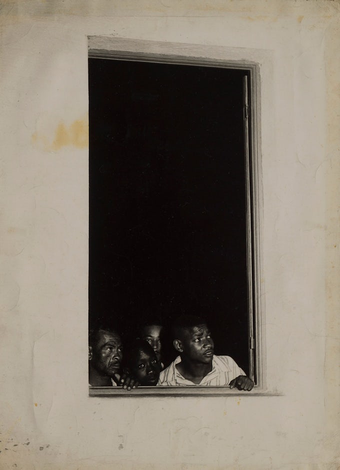 Black and white photograph of people looking out of a window