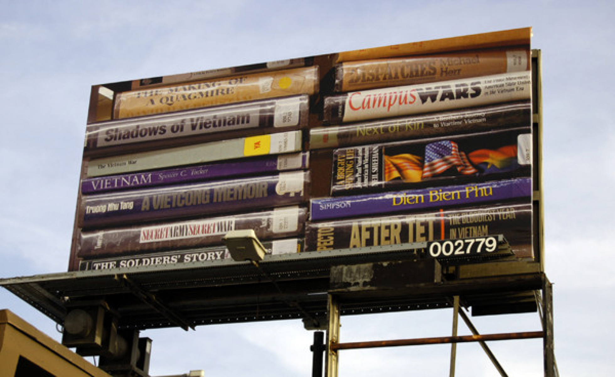 Image of a billboard, showcasing a photograph of Fletcher. Includes stacked books, all related to the American military in Vietnam during the Vietnam War.